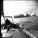 Image of Miriam at wheel, Melville Bay. Icebergs beyond
