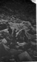 Image of 3 Eskimos [Inuit] among rocks