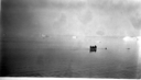 Image of Eskimos [Inuit] in an open boat near a seal? Float
