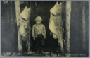 Image of Small boy in period dress with large hanging fish;(message from Mrs. G.K. Sabin)