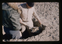 Image of Engineer samples soil in test pit at 3" intervals; Klick and Craven