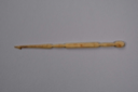 Image of Dark colored ivory crochet hook rounded at wide end, then oval shape, then recta