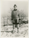 Image of Miriam MacMillan in her yard wearing Eskimo [Inuit] outfit. Hair in topknot