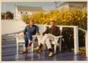 Image of Miriam and Donald MacMillan sitting on their terrace by yellow daisies