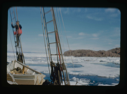 Image of The Bowdoin in ice pack. Donald MacMillan in rigging.