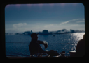 Image of Donald MacMillan sitting on deck. Icebergs beyond.