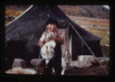 Image of Eskimo [Inuk] boy holding dog in front of tent