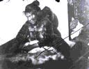 Image of Inuit woman working on furs; baby in hood