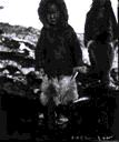 Image of Young Inuit boy in furs holding game of skill