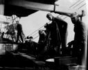 Image of Crewmen working on deck, one using camera