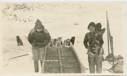 Image of Inuit family repairing sledge. Dogs at rest