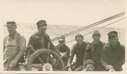 Image of Crew members by wheel. L>R: William Lewis, Richard Goddard, John Jaynes, Don Mix?, Donald MacMillan, ? and Ralph Robinson, seated