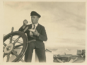Image of Donald MacMillan by wheel, eating, perhaps, the last ice cream.