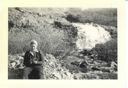 Image of Martha Burt sitting near Bluie West 1 waterfall in spring