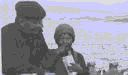 Image of Crewman with Eskimo [Inuk] boy aboard. Boy is eating Cracker Jacks
