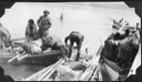 Image of Eskimos [Inuit] tieing up at dock