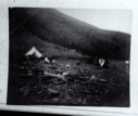 Image of Tent on rocky terrain; Inuit and open boat on shore  