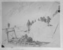 Image of Sledge with partial load; seven Inuit by igloo [iglu]  