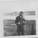 Image of Innu man holding two young pups [Uniam (William) Katshinak]