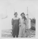 Image of Two young Indian [Innu] women wearing berets, by large tent