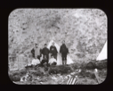 Image of Seven expedition members by tent and pole with U.S. flag
