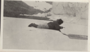 Image of Inuit lying on ice, jigging for fish