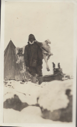 Image of Man by tupik with reindeer (?) on his back. Note mittens on upstanders