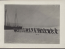 Image of Many men and women pulling rope toward moored vessel