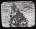 Image of Two Inuit and many dogs in dory