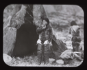 Image of Inuit woman with pipe standing by tupik; 2nd one near