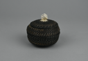 Image of black and white baleen basket with a (gaming) die as finial