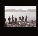 Image of Six crewmen photographing an Inuit man, sitting