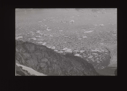 Image of Looking down to crewman on rocks, waving. Ice beyond. Glacier in foregroun [b&w]