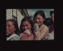 Image of Three smiling school girls. Donald MacMillan in background