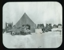 Image of Large tent. Two Inuit men seated on furs, one using binoculars, one with pipe...