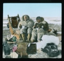 Image of Elmer Ekblaw and Inuit man [Esayoo] sitting on sledge to eat. Tea kettle near