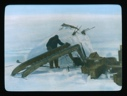 Image of Man by snow igloo working on runners of inverted sledge. Wooden crates near