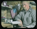Image of Harrison Hunt seated at desk reading. Small flag and books near