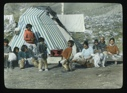 Image of Several Inuit women and children with a team member outside tent ....