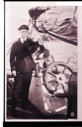 Image of Donald MacMillan standing by wheel, with arm around dog