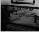 Image of Donald MacMillan looking at map in the BOWDOIN's chart room