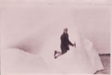 Image of Man kneeling on icy incline, holding pick axe