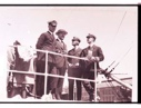 Image of Four men by upper rail of ship. Donald MacMillan on the right.