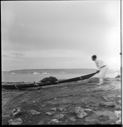 Image of Eskimo [Inuk] man launching (or hauling) kayak
