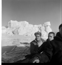 Image of Three crewmen sitting by rail, iceberg beyond. Tiger Burch in center