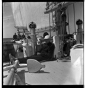 Image of John Bodet sitting on deck near anchor, others beyond at wheel