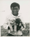 Image of Inuit boy holding two pups [Angussuanguaq Duneq]