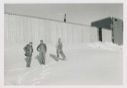 Image of Three men by metal (?) wall, Thule AFB