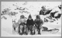 Image of Abram, E-took-a-suk (Ittuksuk) and Ka-ko-tee-a seated on a dog sledge