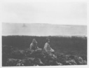 Image of [Two men sitting near shore, Bowdoin in distance]